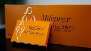 photo of two orange boxes, one larger and one small, labeled "mifeprex" sitting on a table 