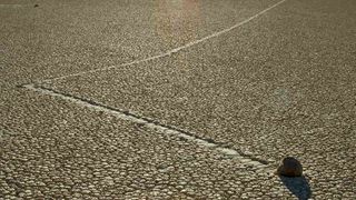 A view of a sailing rock with its track featuring a sharp bend on Racetrack Playa.