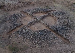 A burial mound made out of small stones with a cross shape intersecting it