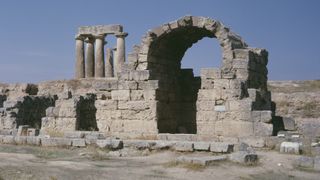 A photo of ruins with an arch, wall, and fluted columns