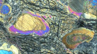 A microscope sample showing shiny rainbow-colored layers of rock